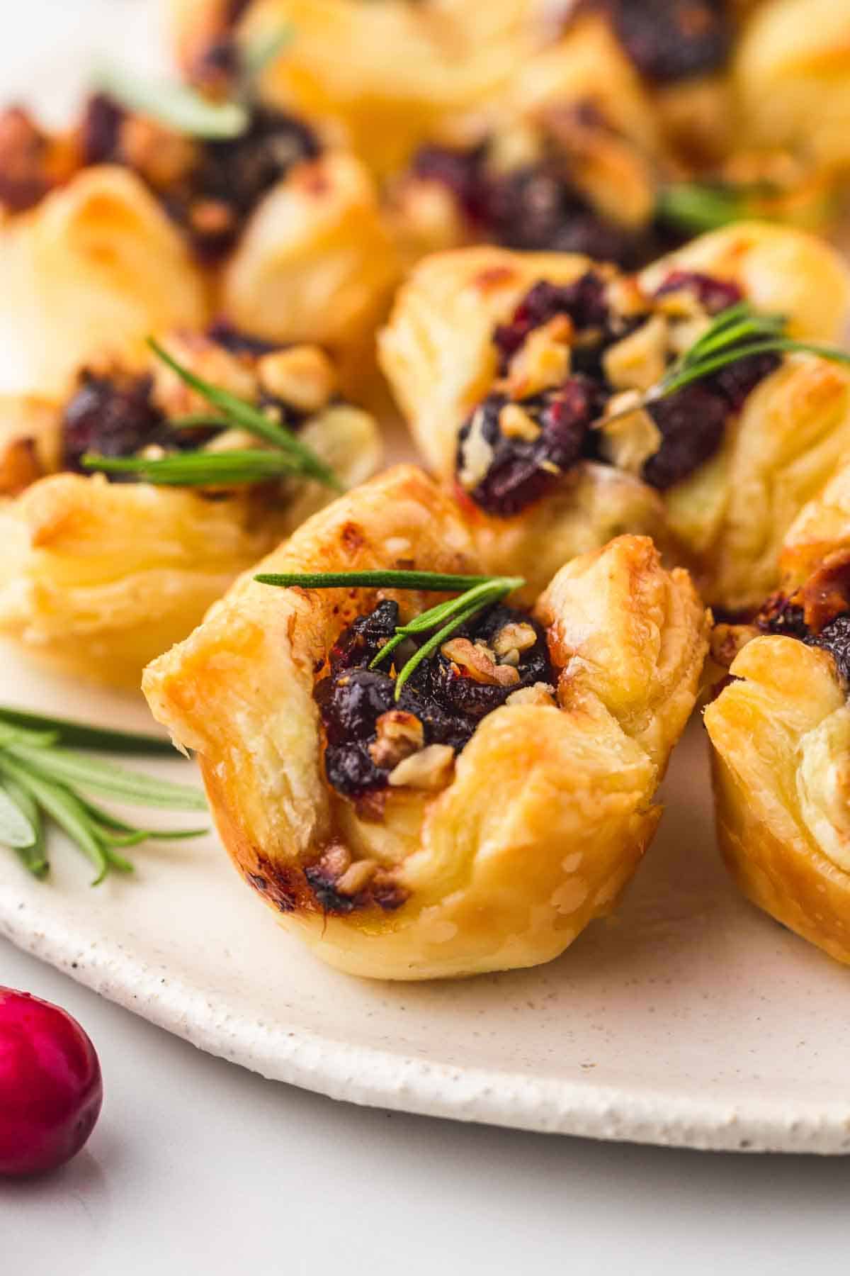 These easy cranberry brie bites make the perfect appetizer that tastes and looks fancy! Gooey melty cheese with tart cranberry sauce wrapped in a golden, buttery, and flaky puff pastry, to make these bite-sized snacks or appetizers for your next holiday gathering!