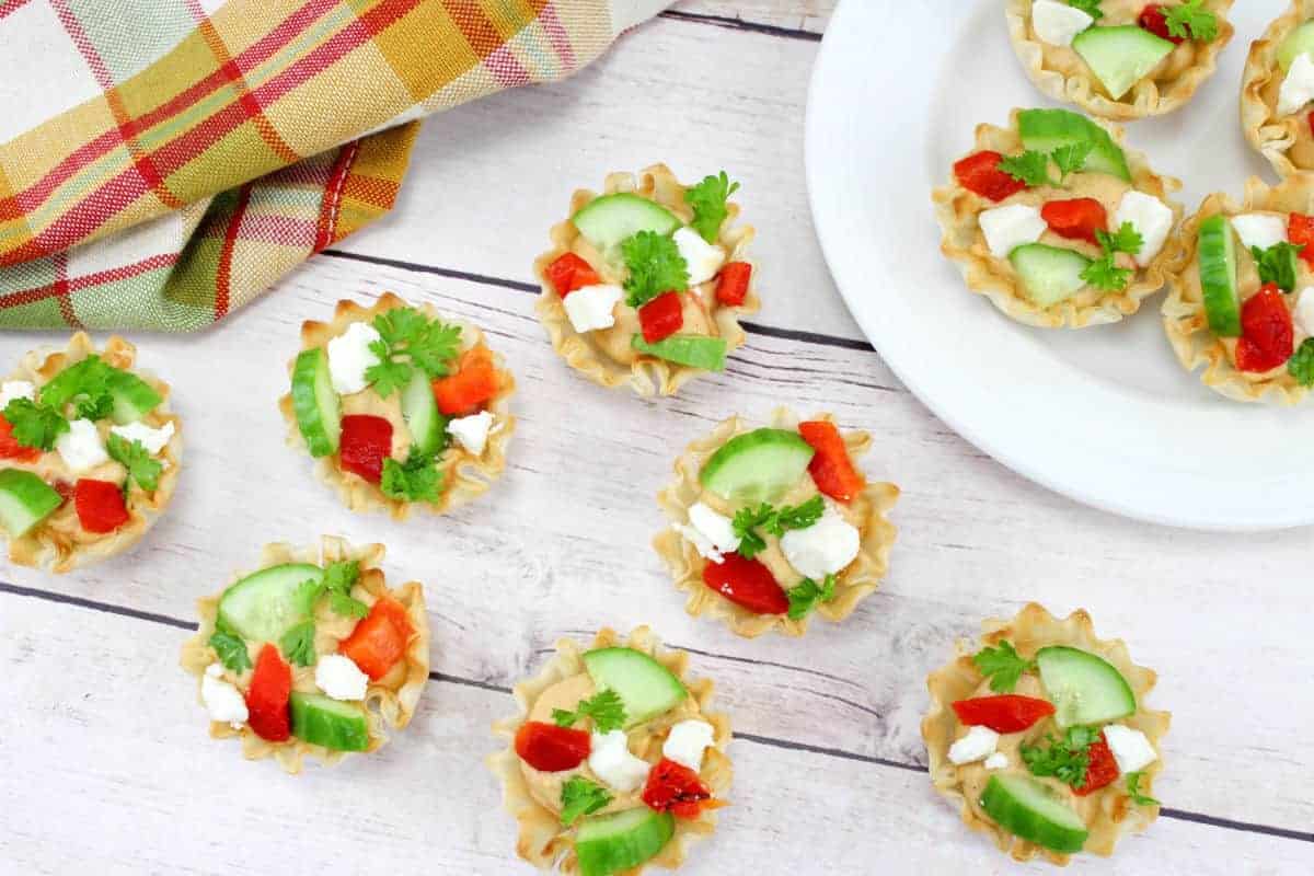 These cucumber hummus appetizers are a hit at parties and make a delicious finger food! Made with crisp cucumber, creamy hummus dip and flavorful roasted red peppers, everyone will love this tasty bite! This hummus appetizer recipe is super easy to customize and makes a great healthy snack for any party.