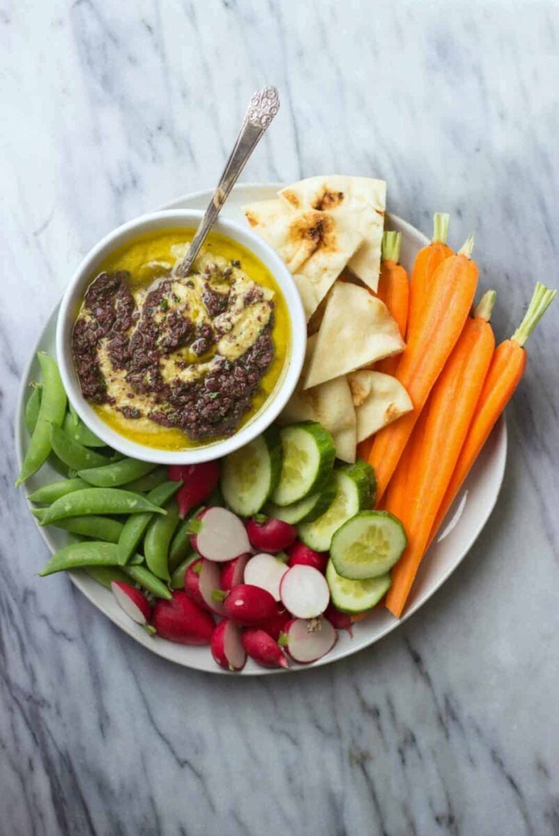 Olive Hummus is the star of this appetizer platter! Homemade hummus with olive pesto, served with fresh vegetables and pita.