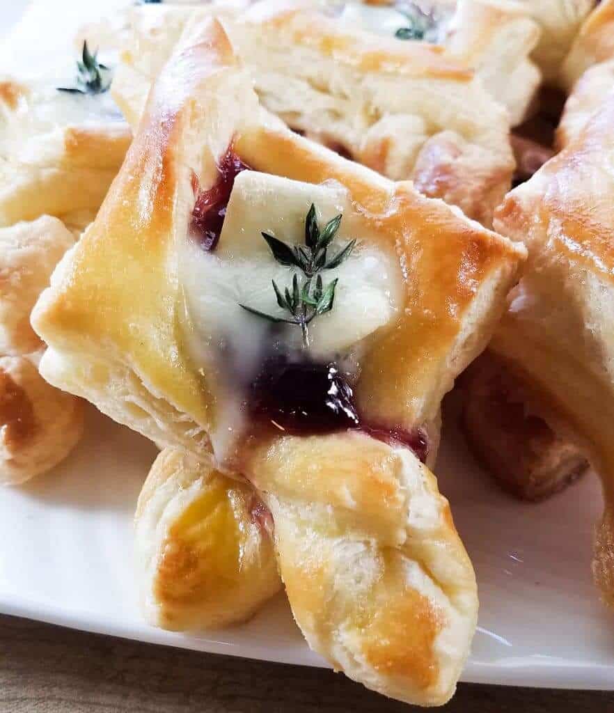 Throw a holiday party in style with this easy puff pastry recipe filled with raspberry jam, brie, and a festive sprig of thyme.