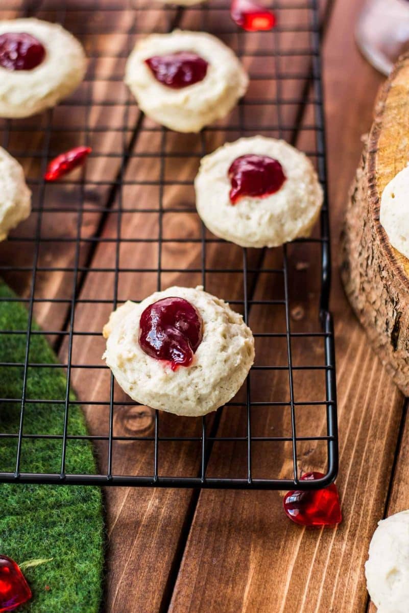 Gorgeous raspberry cream cheese thumbprint cookies on black cooling rack.