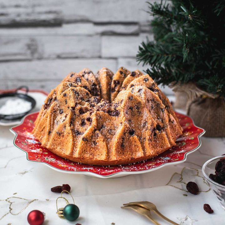 Gorgeous cranberry bundt cake with chocolate chips, cinnamon, and of course dried cranberries. Placed on a red plate.