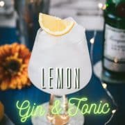 Gorgeous glass filled with a refreshing lemon gin and tonic. Placed on blue wooden ground.