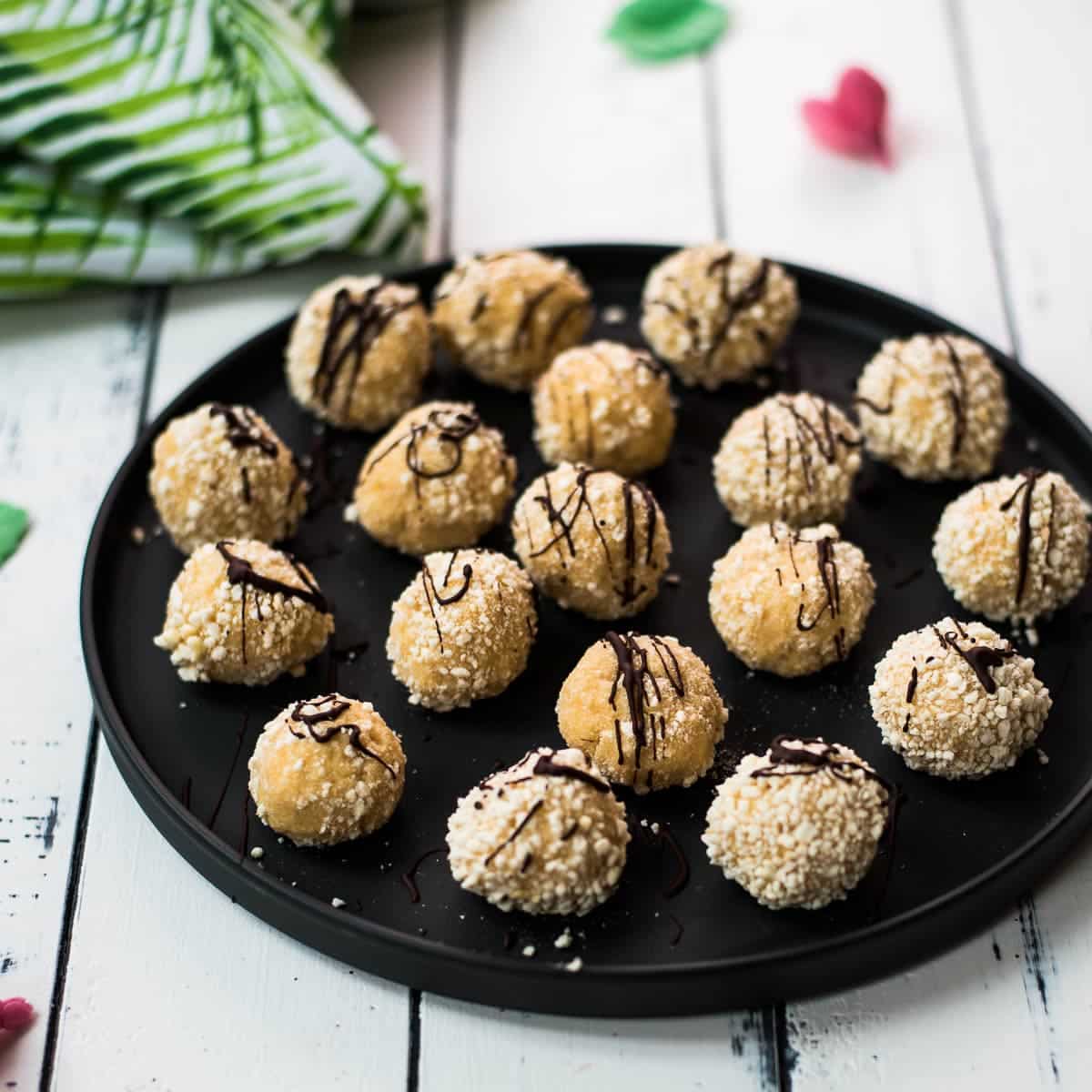 Gorgeous mascarpone eggnog cookies, rolled in ladyfinger crumbs and drizzled with chocolate sauce. Placed on black serving plate.