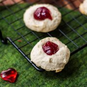 Gorgeous raspberry cream cheese thumbprint cookies on black cooling rack.