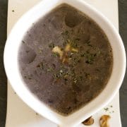 white soup bowl with chestnut porcini mushroom soup on dark ground with roasted porcini mushrooms