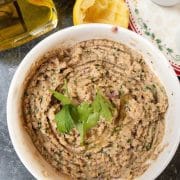 homemade hummus in a bowl next to squeezed lemon, olive oil and tableware