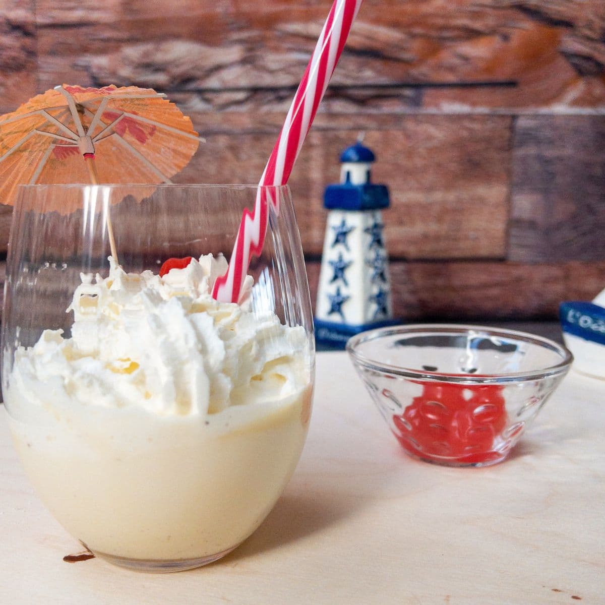 Glass with homemade eggnog milkshake, topped with whipped cream and a yummy cocktail cherry on top.