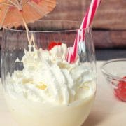 Glass with homemade eggnog milkshake, topped with whipped cream and a yummy cocktail cherry on top.