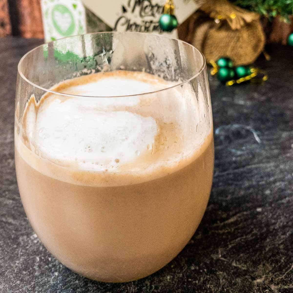 Dinking glass filled with eggnog and hot chocolate with a yummy milk foam on top!