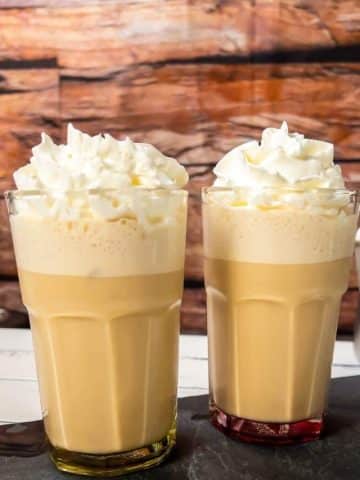 Glass filled with creamy iced coffee, garnished with whipped cream.