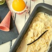 Loaf pan filled with homemade vanilla ice cream. With pink ice cream cones alongside.