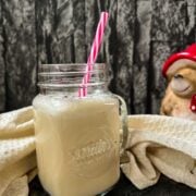 Drinking glass with plastic straw and ready to drink caramel milk. Beige linen in the back.