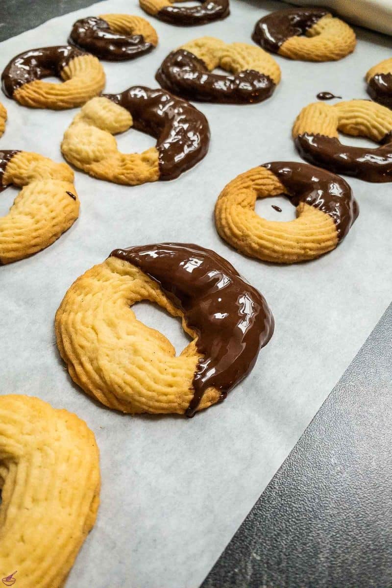 Butter cookies dipped half way in dark chocolate couverture. 