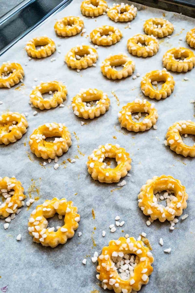 Cut out sour cream cookies after baking. Spread with egg yolk and sprinkled with nib sugar. 