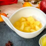 White ceramic bowl with apple compote. Decorated with apples, a cute hedgehog and orange flowers placed on the side.