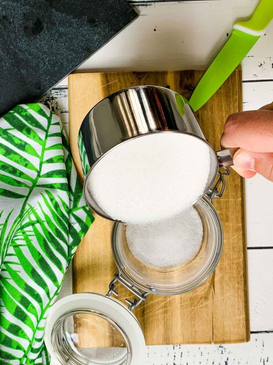 Pouring in a cup of granulated sugar into a preserving jar. 