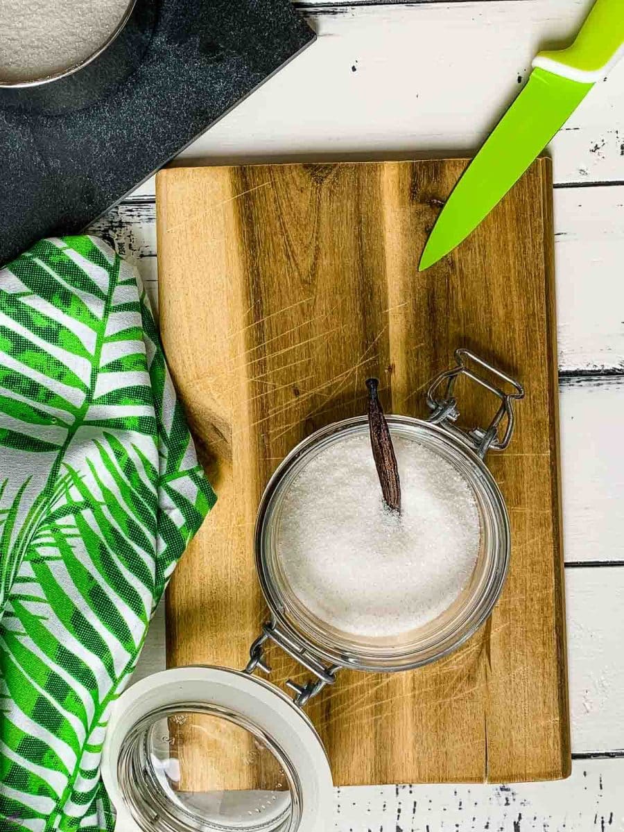 Adding vanilla bean to preserving jar filled with granulated sugar.