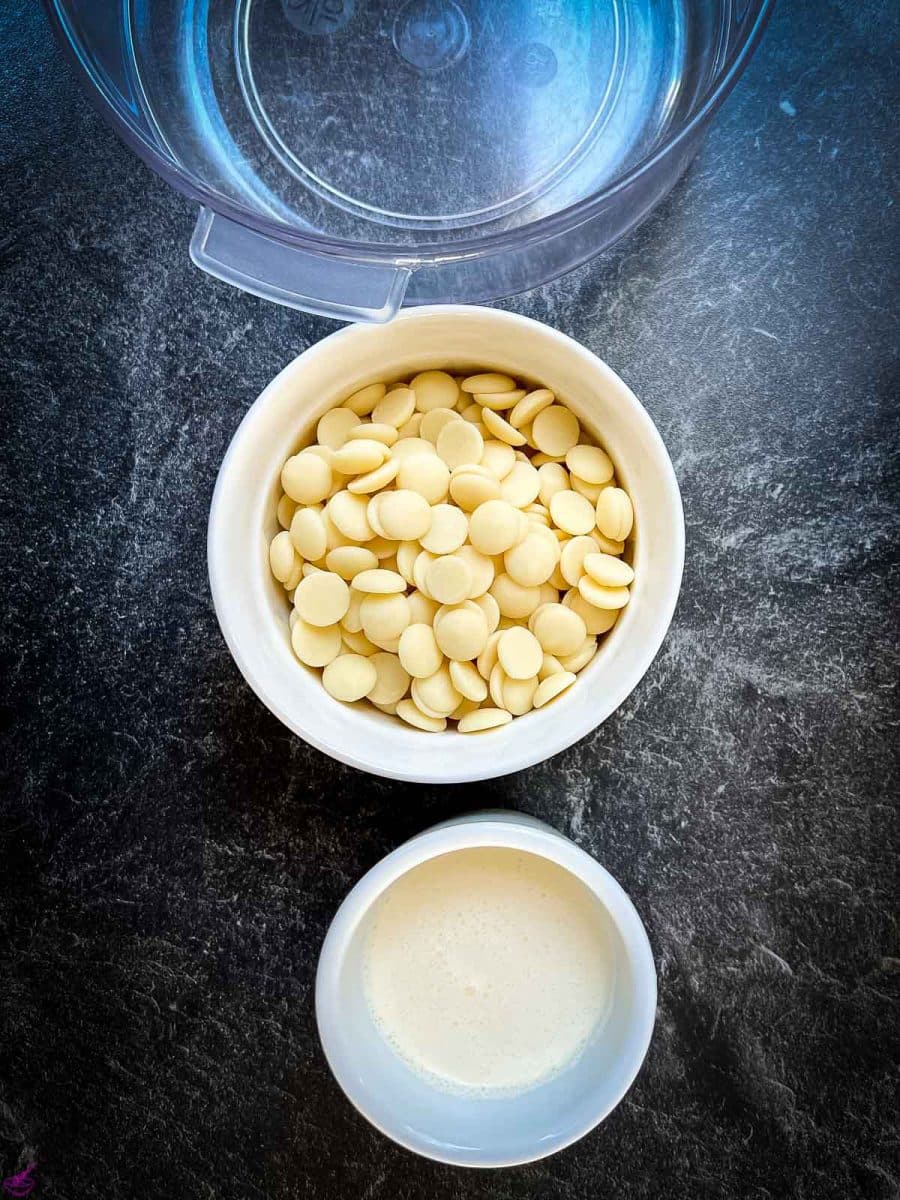 Hot cream and white chocolate chips next to a mixing bowl. 