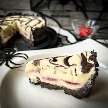 Slice of no bake raspberry Oreo cheesecake on white plate.