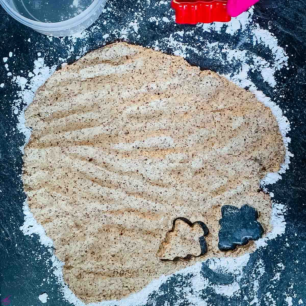 Cinnamon star cookie dough getting cut out with a tree shaped cookie cutter.