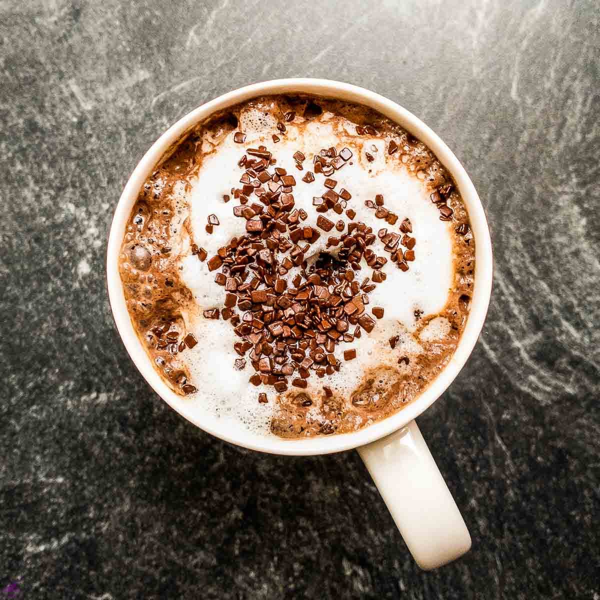 Hot chocolate topped with milk foam and chocolate sprinkles.