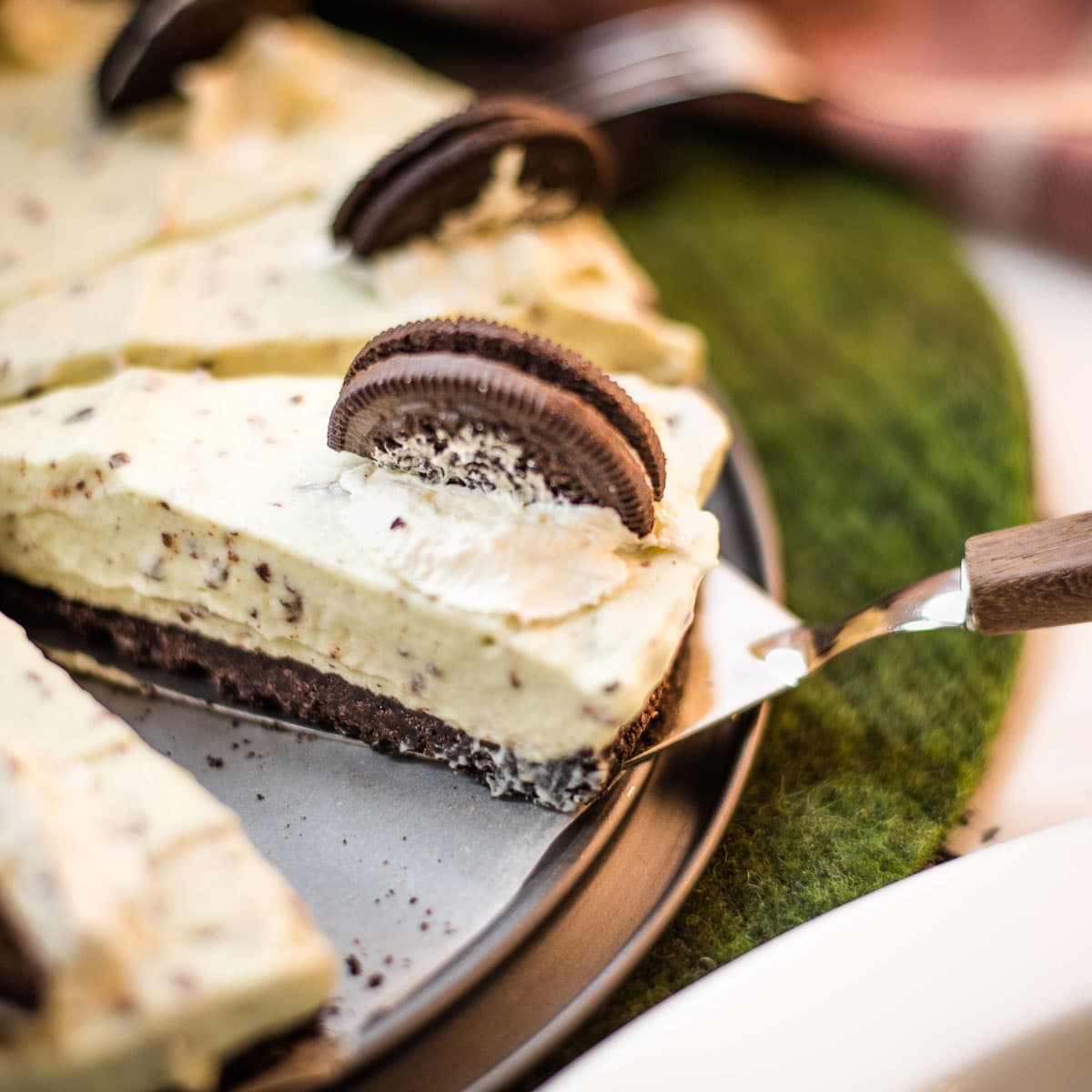A refreshing green no bake mint chocolate cheesecake with Oreo crust and After Eight pieces inside the cream cheese filling.