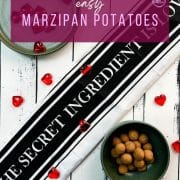 Delicious marzipan potatoes in a dark green bowl on white wooden ground.