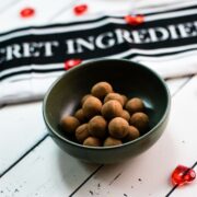 Delicious marzipan potatoes in a dark green bowl on white wooden ground.