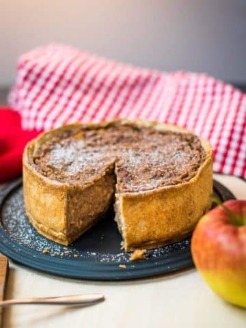 Delicious apple tart with a slice cut out. Dusted with powdered sugar.