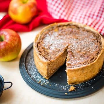 Delicious apple tart with a slice cut out. Dusted with powdered sugar.