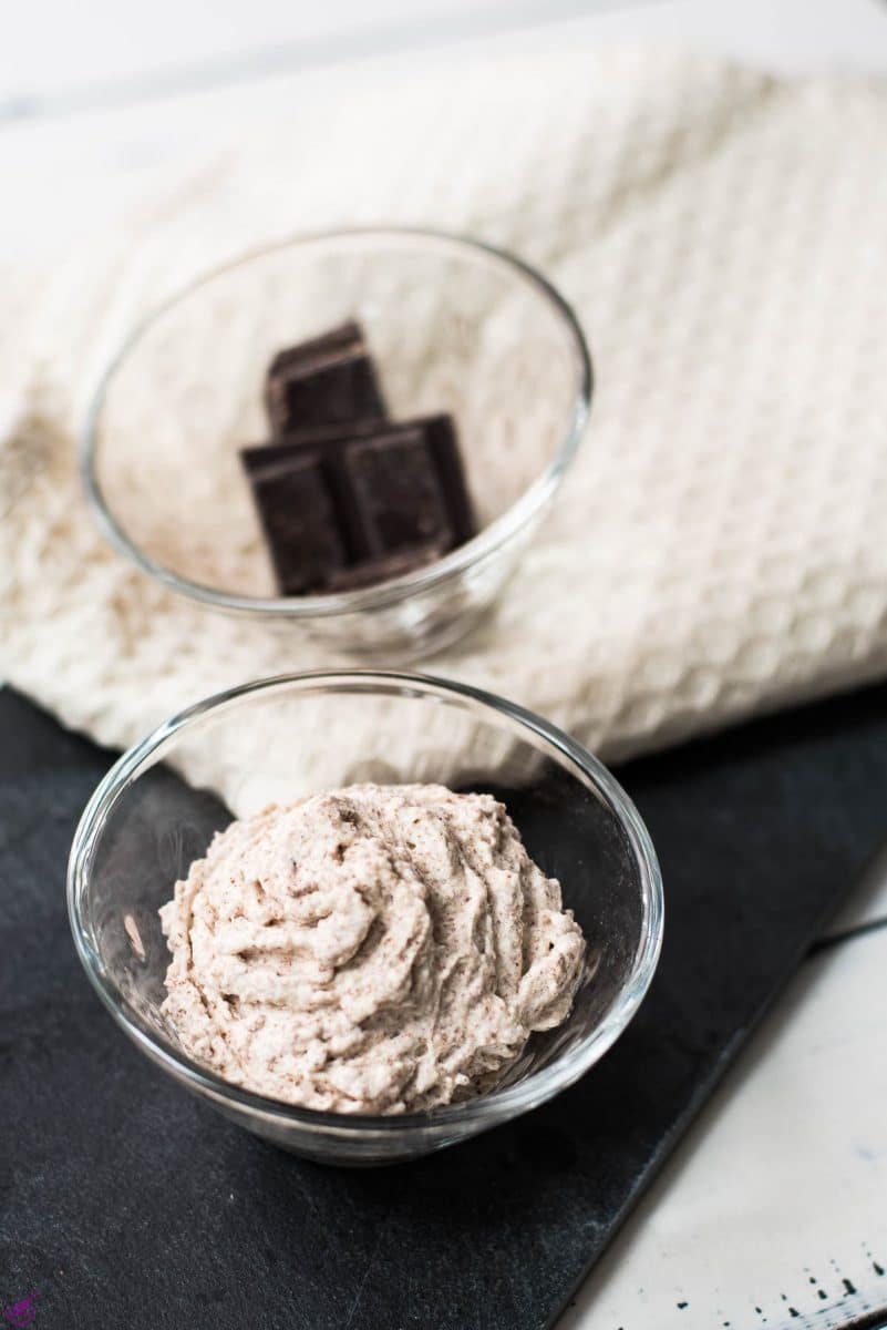 Two glass cups, one filled with delicious chocolate flavored whipped cream, the other with two small chocolate bars.