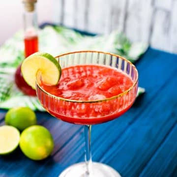 Gorgeous cocktail glass, with golden rim, filled with frozen strawberry daiquiri.