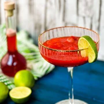 Gorgeous cocktail glass, with golden rim, filled with frozen strawberry daiquiri.