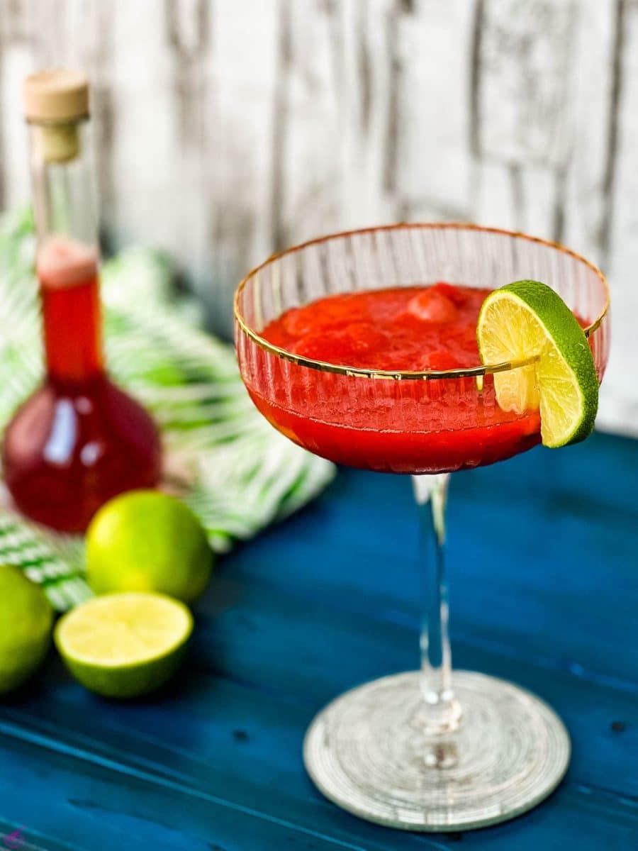 Gorgeous cocktail glass, with golden rim, filled with frozen strawberry daiquiri.