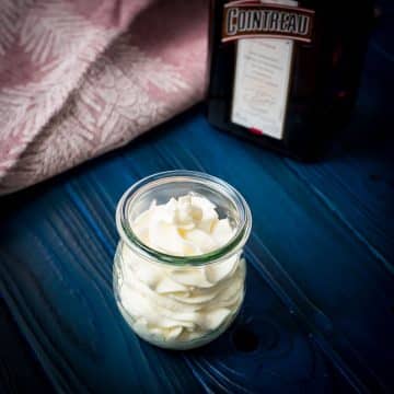 A tulip Weck jar filled with delicious orange flavored whipped cream on dark blue wooden floor.