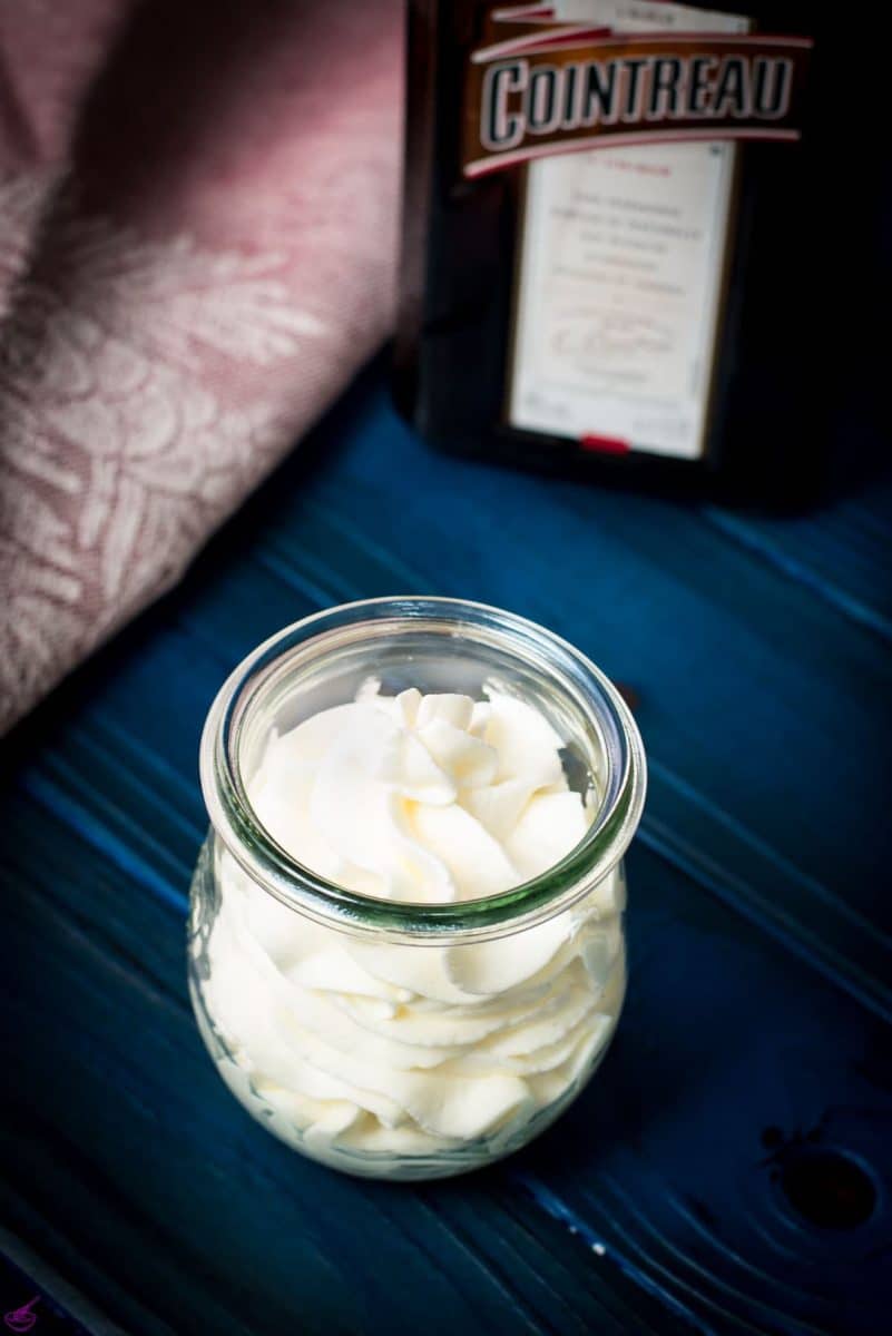 A tulip Weck jar filled with delicious orange flavored whipped cream on dark blue wooden floor.