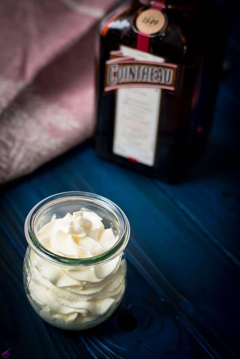 A tulip Weck jar filled with delicious orange flavored whipped cream on dark blue wooden floor.