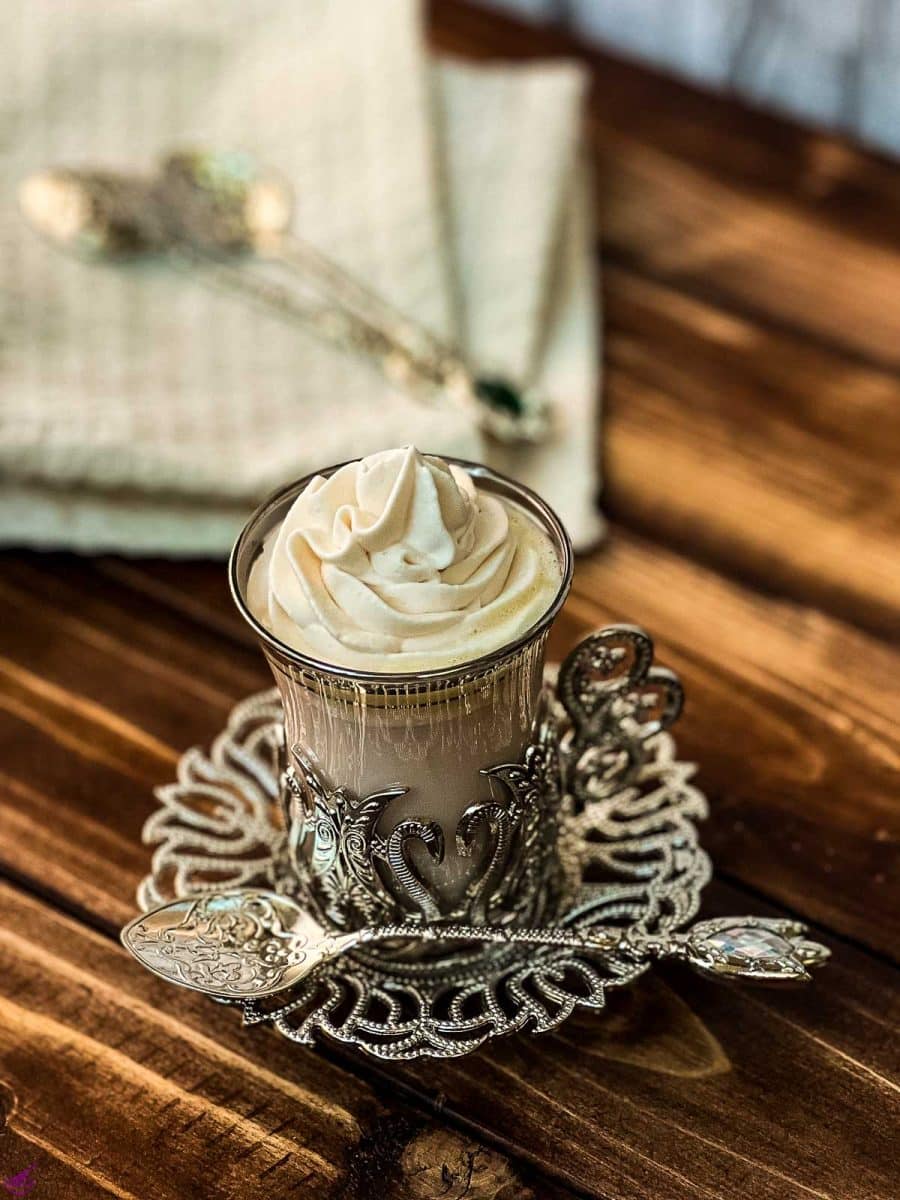 A gorgeous glass filled with strawberry hot chocolate and topped with a rosette of strawberry flavored whipped cream.