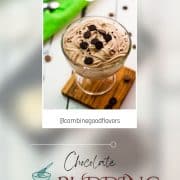 Beautifully textured chocolate cornstarch pudding in a dessert glass. Placed on a wooden coaster on a white wooden floor. Decorated with small pieces of cookies.