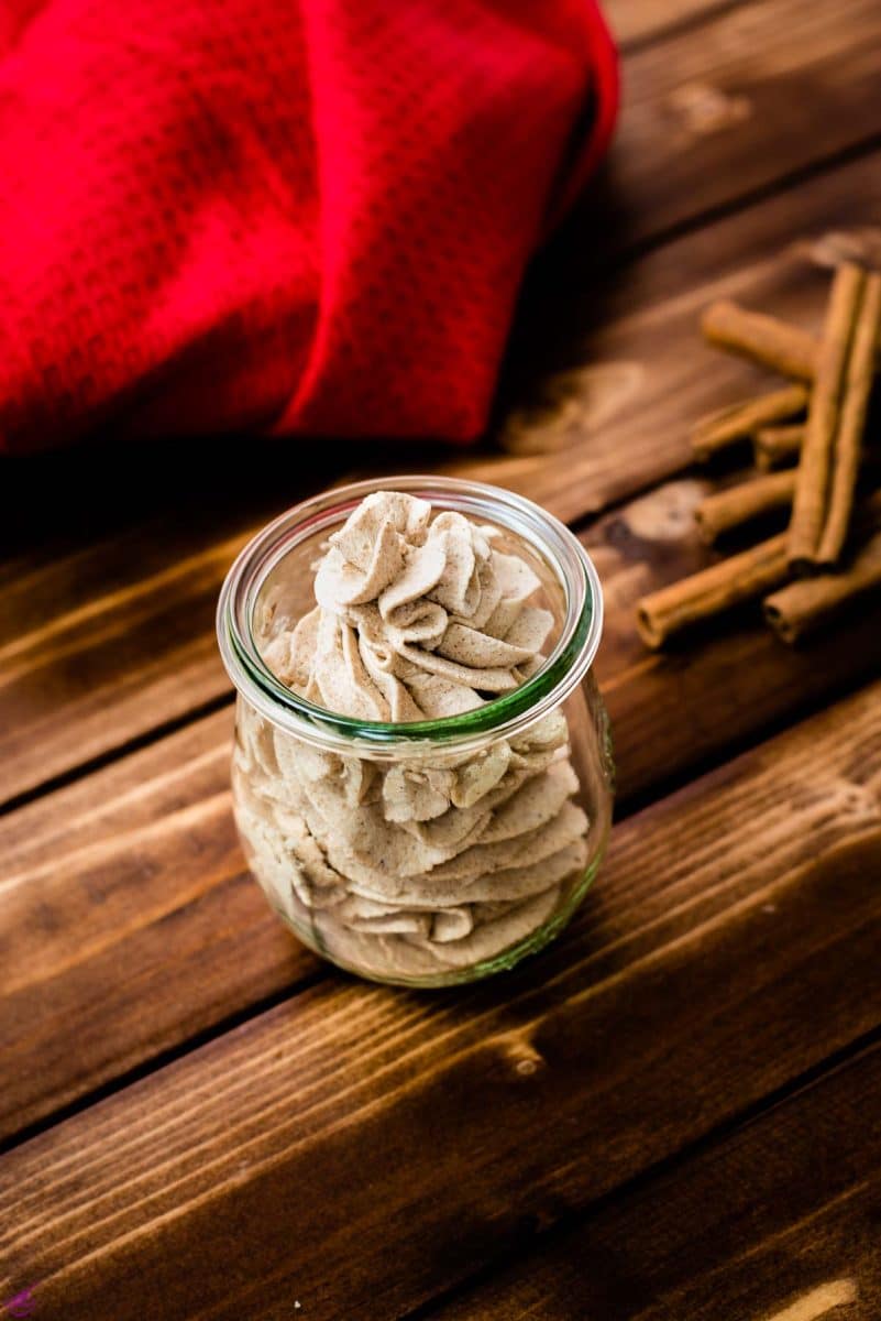 Gorgeous cinnamon whipped cream, in tulip formed Weck glass on a wooden floor.