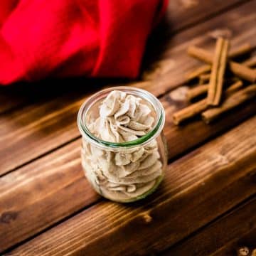 Gorgeous cinnamon whipped cream, in tulip formed Weck glass on a wooden floor.