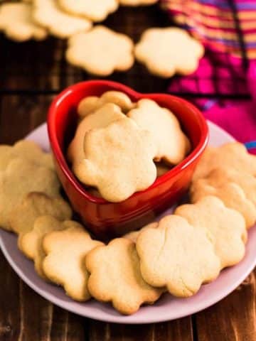 Delicious sugar cookies, placed on pretty plates on dark wooden background.