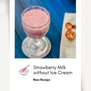 Cute and delicious pink strawberry milk in a gorgeous serving glass. Placed on a glass coaster on blue wooden ground.