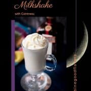 Delicious white Cointreau (orange liqueur) milkshake for adults on mirror glass coaster and dark blue wooden base.