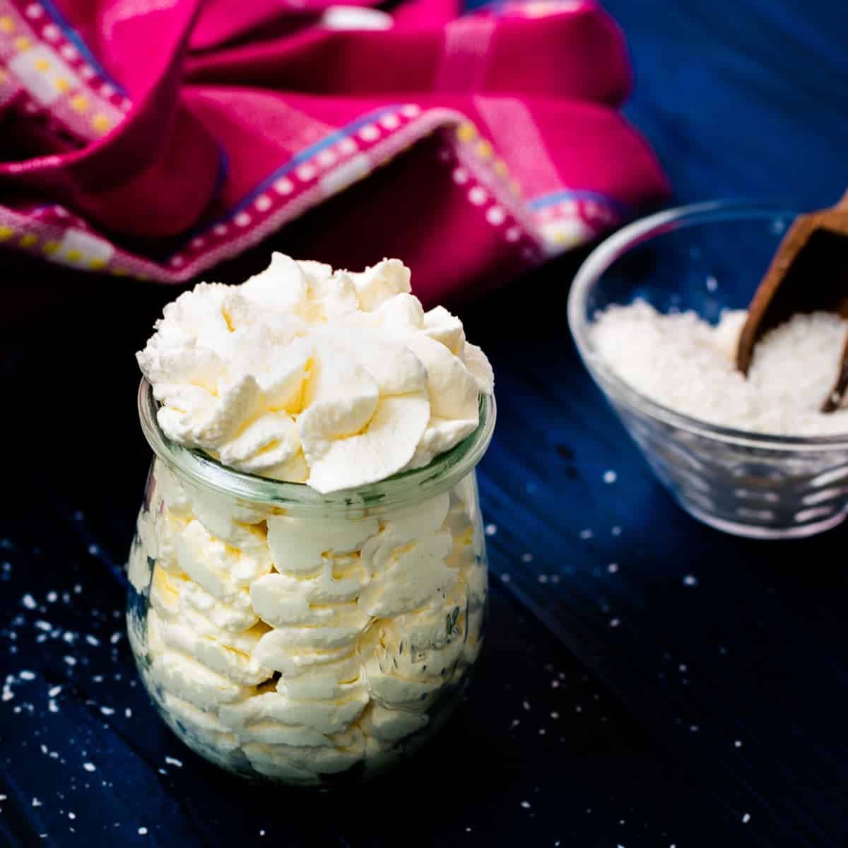 Coconut-flavored whipped cream in a Weck glass, on blue wooden ground.