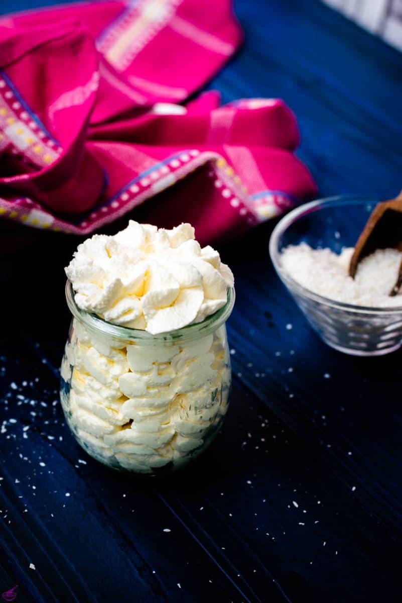 Coconut-flavored whipped cream in a Weck glass, on blue wooden ground.