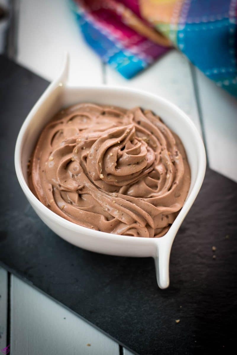 White ceramic bowl filled with delicious dark chocolate pudding on black slate plate.