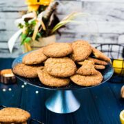 A pile of delicious lemon white chocolate chip cookies on blue cake stand. Standing on a blue wooden board, next to lemons and cookies.
