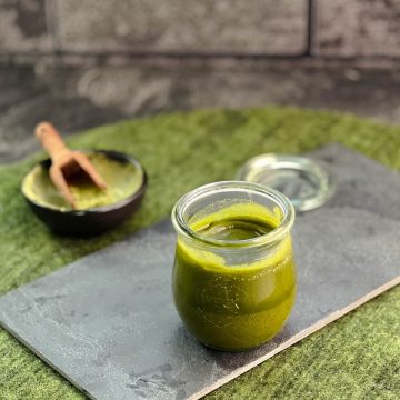 A preserving jar filled with Matcha butter (after cooling) on a slate plate.